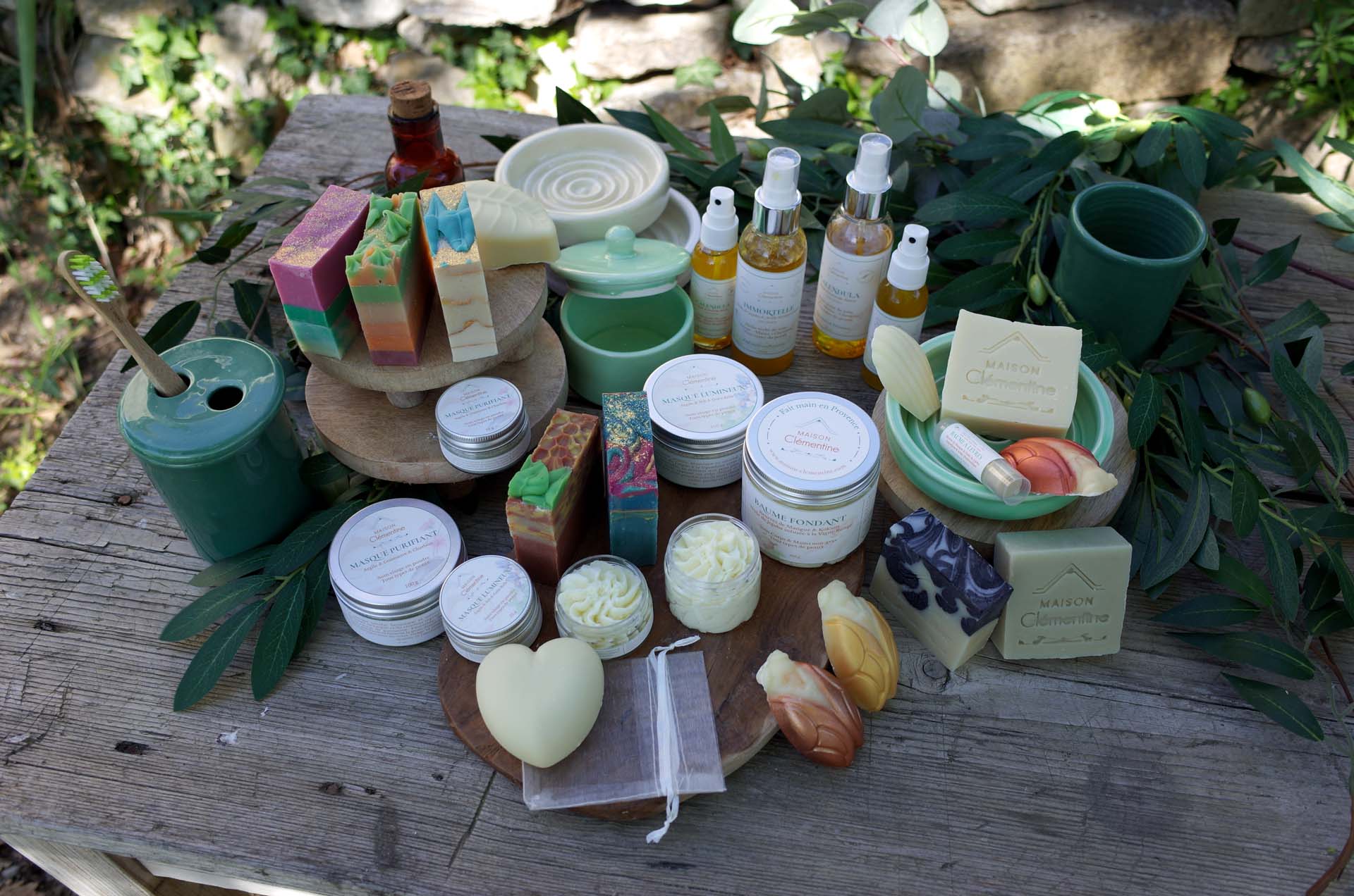 La gamme Maison Clémentine sur une table en bois : savons, pots, flacons et masques avec leurs étiquettes